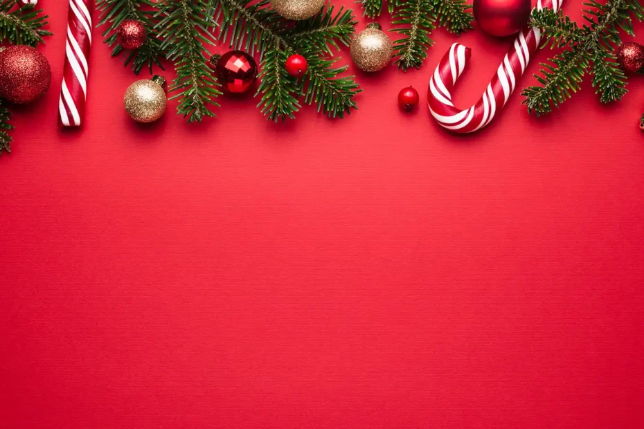 Roter Hintergrund, am oberen Rand Tannenzweige, Weihnachtsbaumkugeln und Zuckerstangen